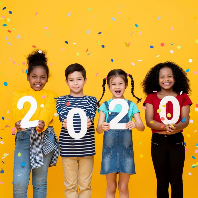 Cute smiling mixed race kids showing numbers 2020 celebrating new year isolated on yellow background
